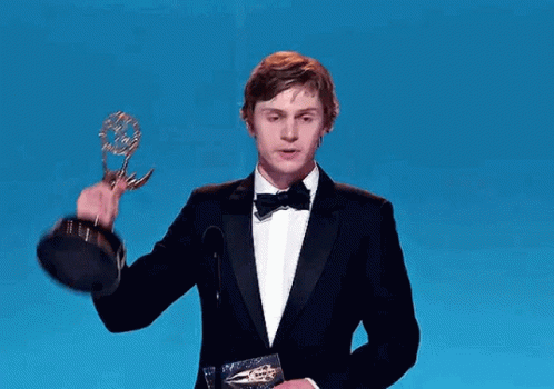 Man in Tuxedo Holding Trophy at Microphone