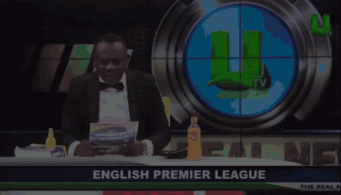 Man in Tuxedo in Front of English Premier League Screen