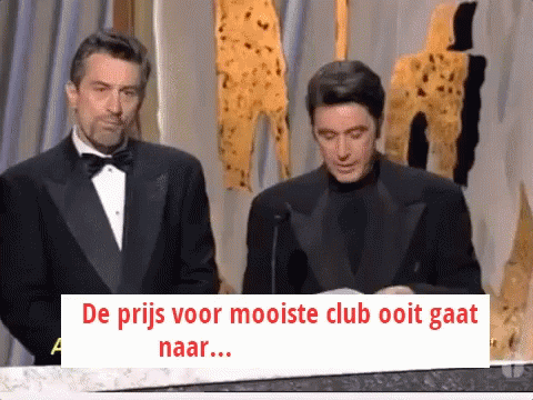 Man in Tuxedo Next to Man With Sign de prijs voor mooiste club ooit gaat