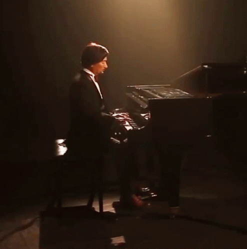 Man in Tuxedo Playing Piano in Dark