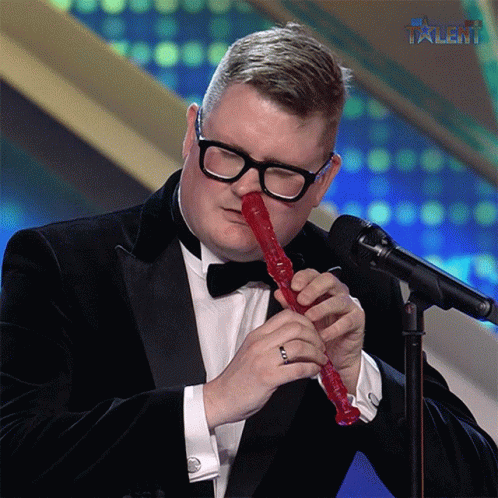 Man in Tuxedo Playing Red Recorder With Talent