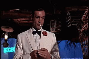 Man In Tuxedo Smoking In Dark Room GIF