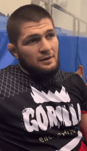 Man In UFC Hat Standing In Front Of Makhachev Time Sign GIF