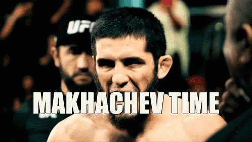 Man In UFC Hat Standing In Front Of Makhachev Time Sign GIF