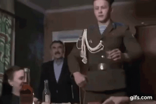 Man in Uniform Holding Shot Glass With Group