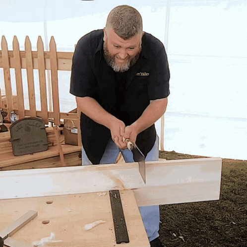 Man in Valley Shirt Cutting Wood With Saw