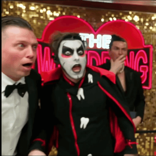 Man in Vampire Costume in Front of Ring Sign