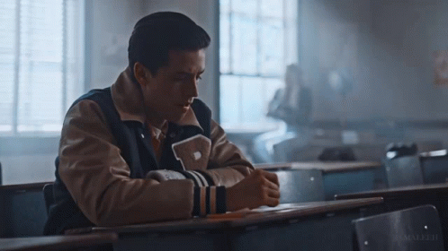 Man In Varsity Jacket With Letter P Sitting At Desk GIF