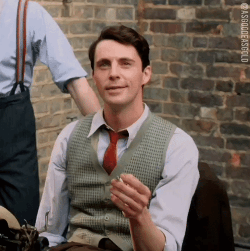 Man in Vest and Tie Smoking by Brick Wall