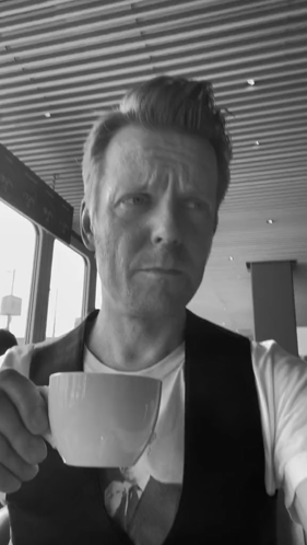 Man in Vest Holding White Cup of Coffee