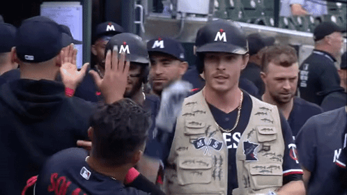 Man in Vest with Letter M Walks Through Crowd