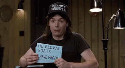 Man in Wayne's World Hat Holding He Blows Goats Have Proof Sign