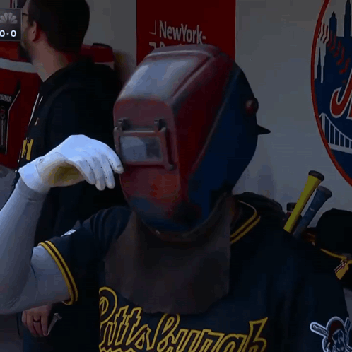 Man in Welding Helmet and Gloves With New York Sign