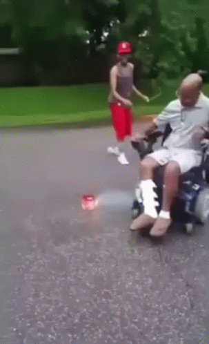 Man in Wheelchair with Leg Bandage Pushed by Boy