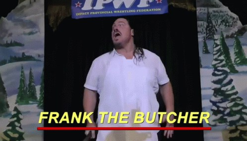Man in White Apron Standing in Front of Frank the Butcher Banner
