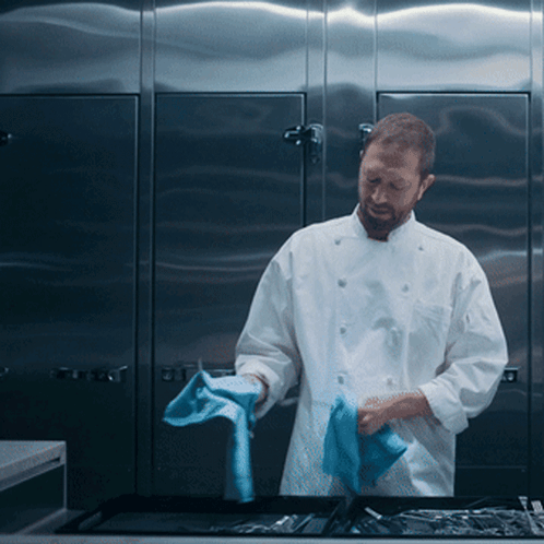 Man in White Chef Uniform Cleaning Tray With Blue Cloth