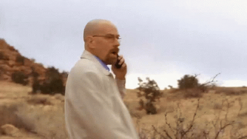 Man In White Coat Talking On Cell Phone In Desert GIF