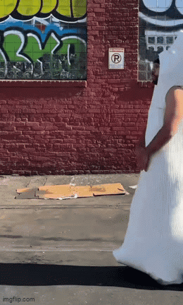 Man in White Costume Walking Past Graffiti Wall
