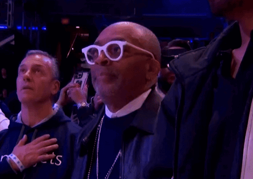 Man in White Glasses With Hand on Heart in Crowd