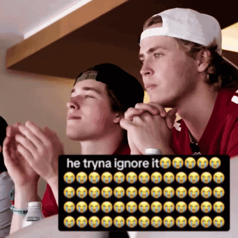 Man in White Hat Sitting Next to Man in Red Shirt Praying