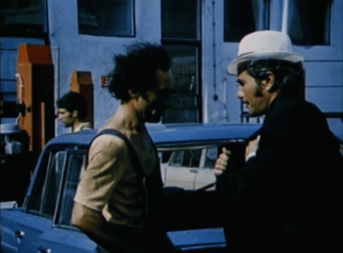 Man in White Hat Talking to Man in Overalls