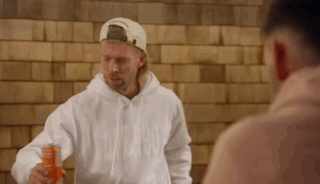 Man in White Hoodie and Hat Holding Orange Juice Can