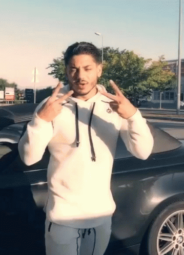 Man in White Hoodie in Front of Black Car