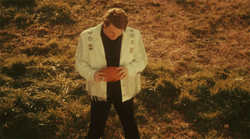 Man in White Jacket Holding Football With Number 1