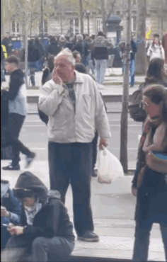 Man in White Jacket on Phone in Crowded Street