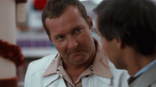 Man in White Jacket Talking to Man in Brown Shirt