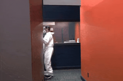 Man In White Jumpsuit In Hallway GIF