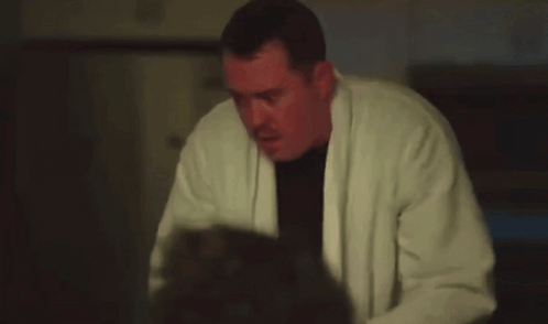 Man In White Robe Holding Gun In Dark Room GIF
