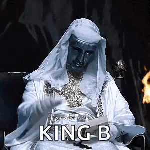 Man in White Robe Reading Book With King B