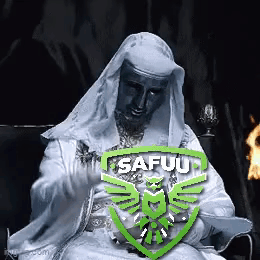 Man in White Robe Sitting in Front of Fire With Safuu Logo