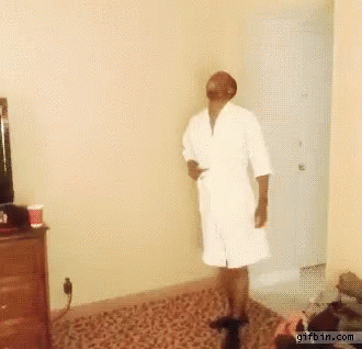 Man in White Robe Standing on Rug in Room