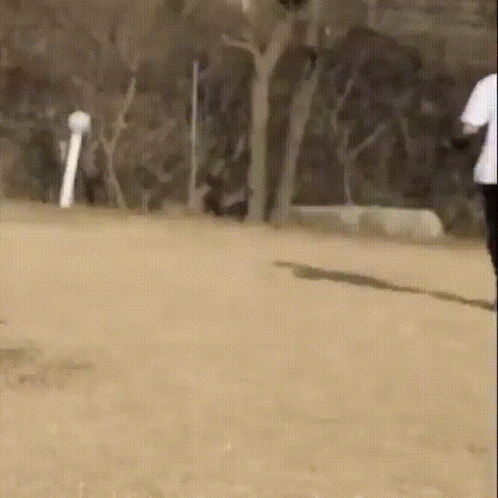Man in White Shirt and Black Pants Running on Dirt Field
