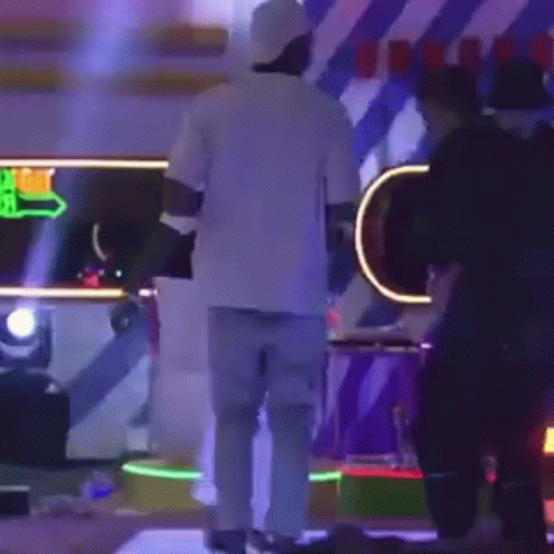 Man In White Shirt And Blue Jeans On Stage With People GIF