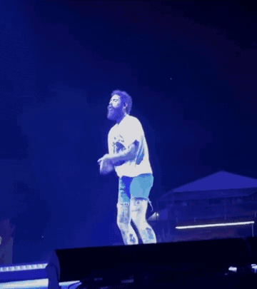 Man In White Shirt And Blue Shorts Dancing On Stage In Front Of Crowd GIF