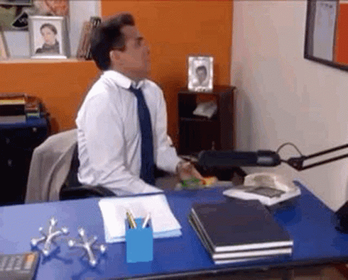 Man In White Shirt And Blue Tie At Desk With Calculator GIF