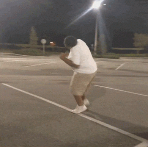 Man in White Shirt and Khaki Shorts Running on Parking Lot
