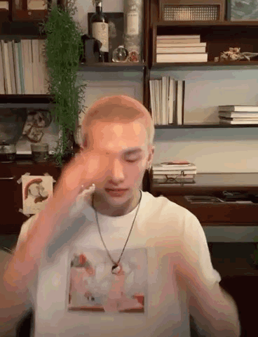 Man In White Shirt And Necklace By Bookshelf GIF