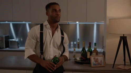 Man In White Shirt And Suspenders Holding Bottle GIF