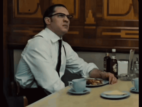 Man in White Shirt and Tie at Table With Plate of Food