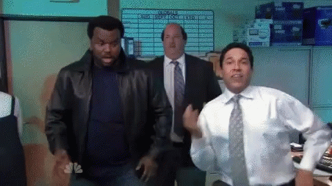Man in White Shirt and Tie Dancing in Front of NBC Sign