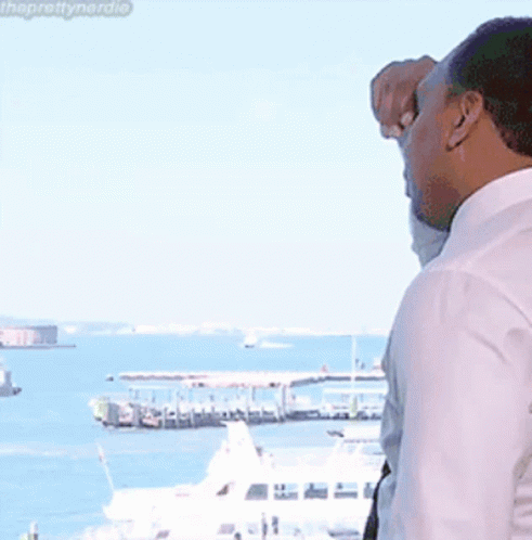Man in White Shirt and Tie Looking Out Window at Ocean