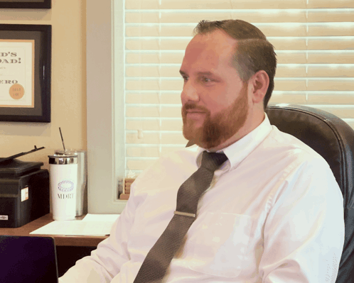 Man in White Shirt and Tie Sitting in Front of Dad Sign
