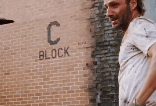 Man in White Shirt at Brick Wall with Block