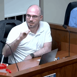 Man in White Shirt at Desk with Laptop and Microphone