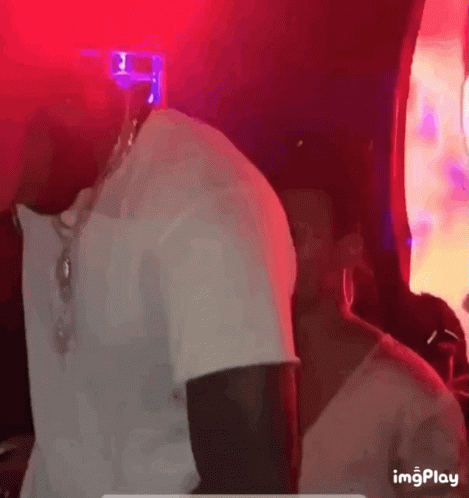 Man in White Shirt Dancing in Dark Room With Red Light