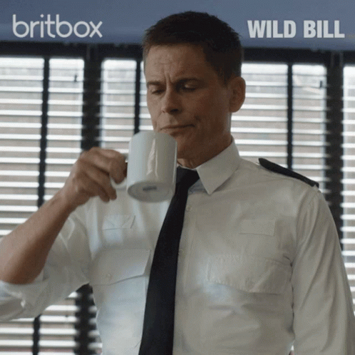 Man In White Shirt Drinking From Mug With Britbox Wild Bill Behind Him GIF
